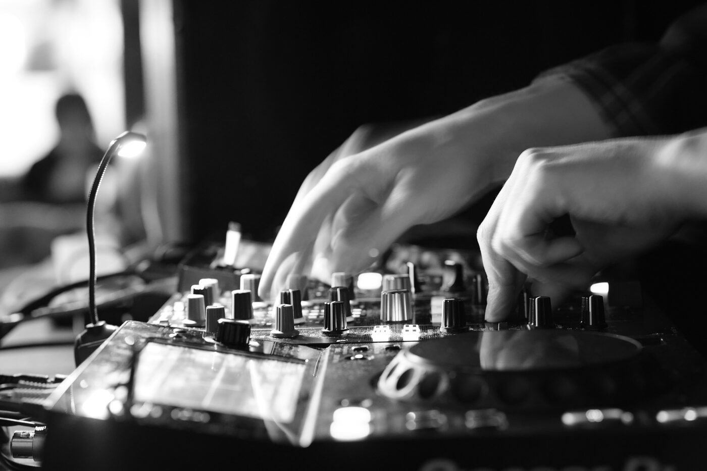 Black and white close-up of hands on a DJ mixer